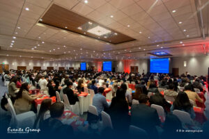 Evento corporativo con asistentes en mesas redondas dentro de un espacio temático automotriz, enfocado en networking y formación profesional